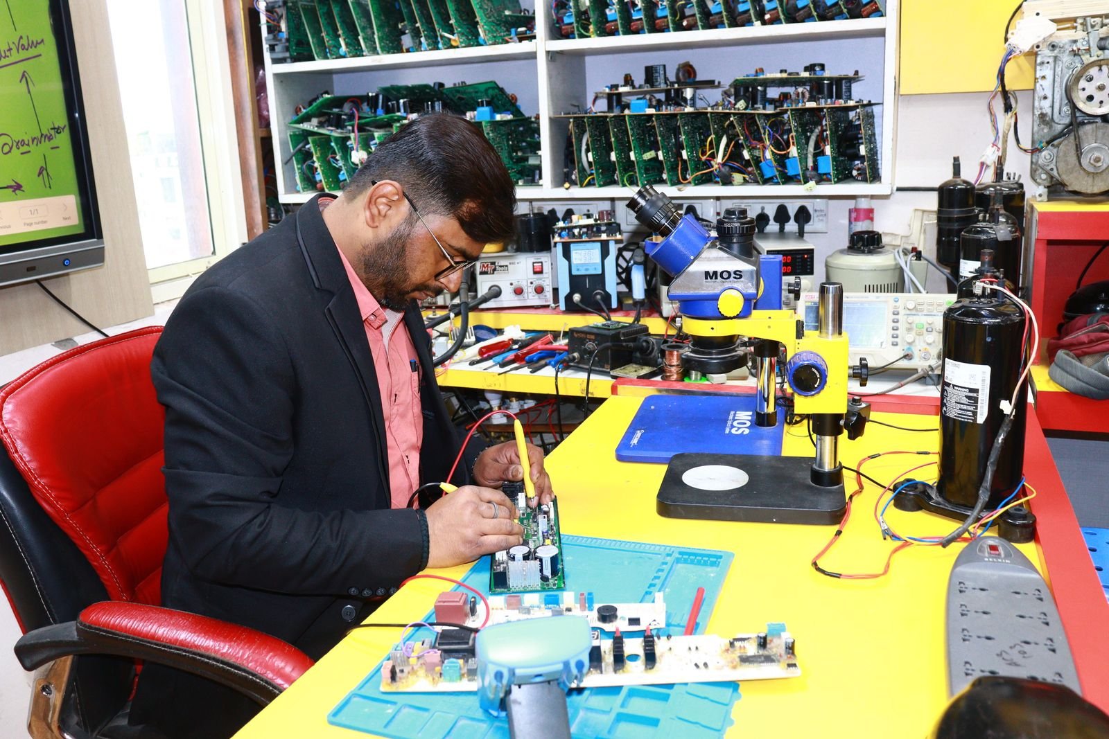 Technician working on a circuit board at an electronics workbench